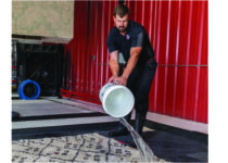 technician pouring water on rug with bucket