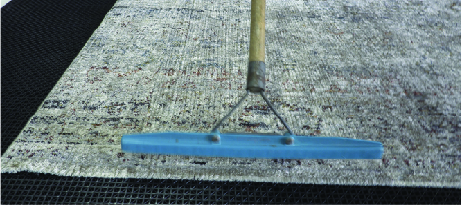 grooming the rug fibers with a rake