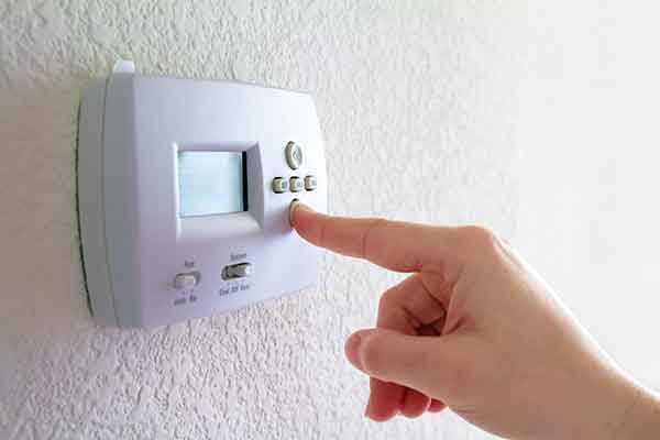 a woman pressing buttons on a thermostat