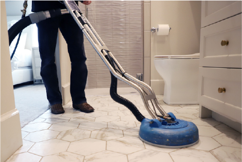 Technician cleaning tile in a bathroom with a blue turbo scrubber.
